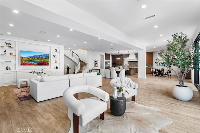 living room with light wood finished floors, visible vents, stairway, built in shelves, and recessed lighting