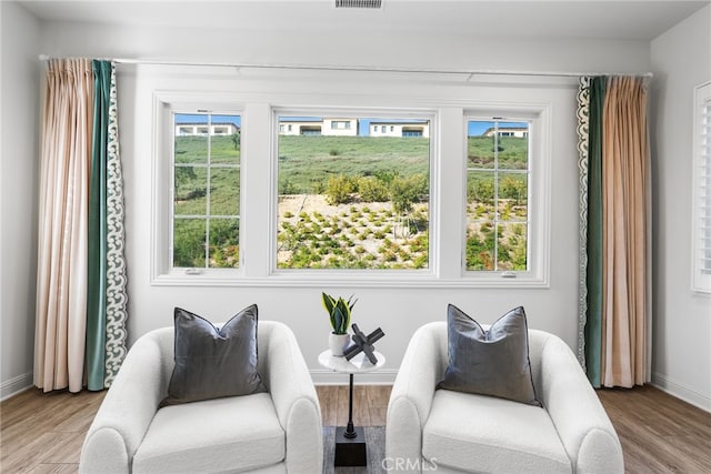 living area featuring plenty of natural light, light wood-style flooring, and baseboards