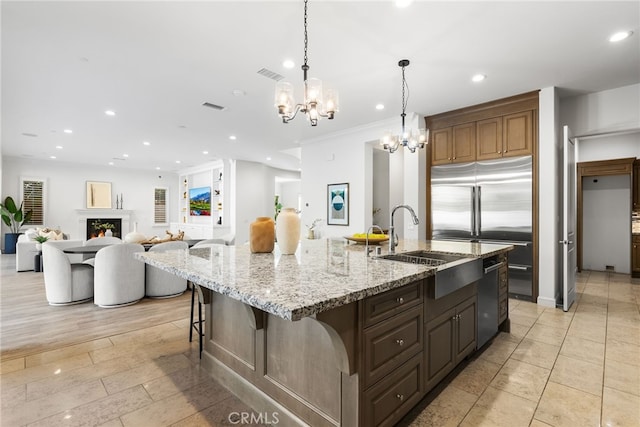 kitchen with a spacious island, a breakfast bar, open floor plan, hanging light fixtures, and a sink