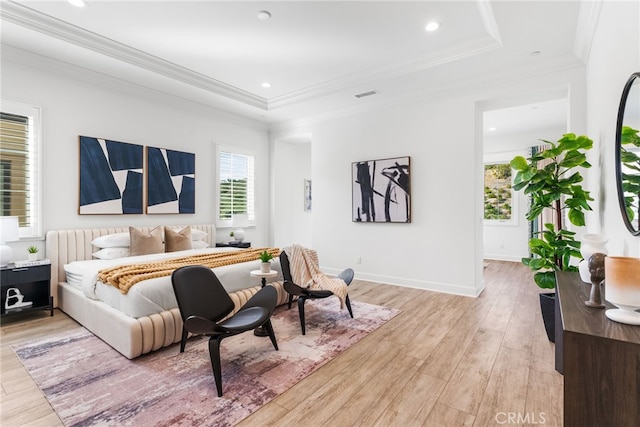 bedroom featuring visible vents, baseboards, light wood-style floors, a raised ceiling, and crown molding