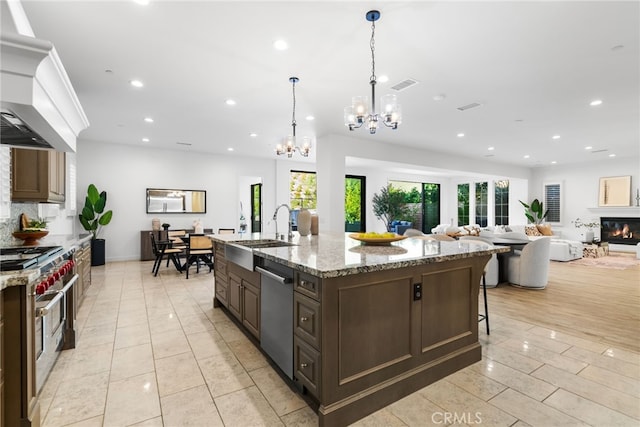 kitchen with a large island, appliances with stainless steel finishes, open floor plan, premium range hood, and a sink