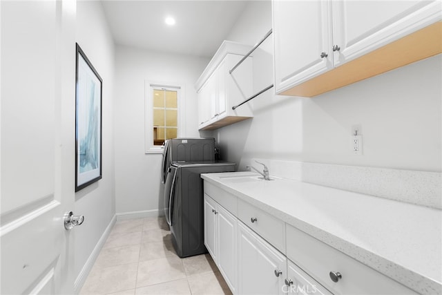 laundry area featuring cabinet space, light tile patterned flooring, a sink, washer and dryer, and baseboards