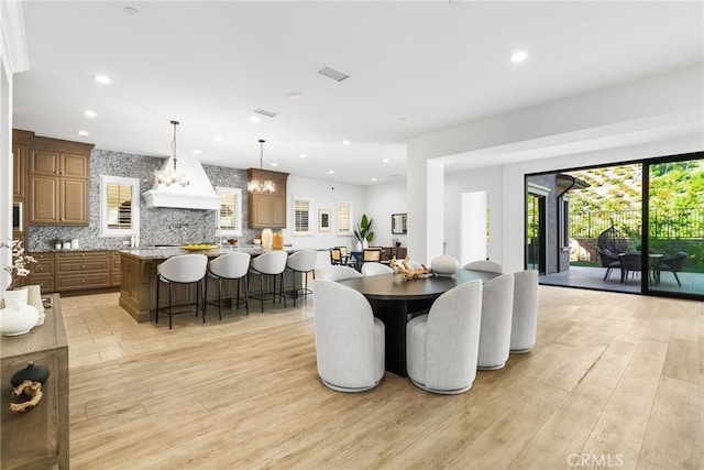 dining space with light wood-style flooring, a notable chandelier, and recessed lighting