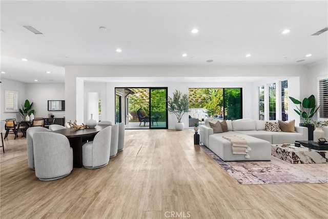 living room featuring light wood-type flooring, plenty of natural light, visible vents, and recessed lighting