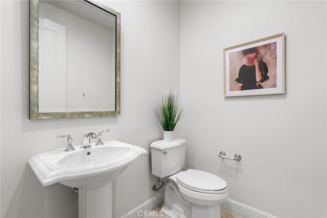 half bath featuring toilet and baseboards