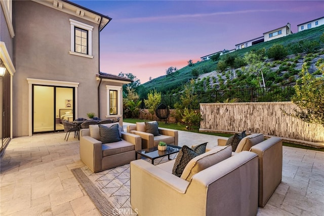 patio terrace at dusk with fence and an outdoor living space