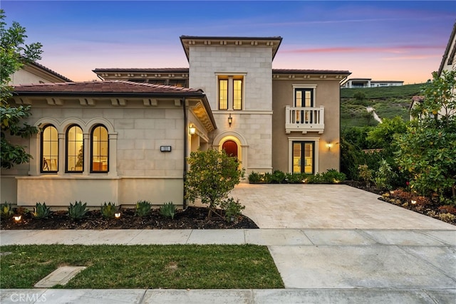 view of front of home with a balcony and decorative driveway