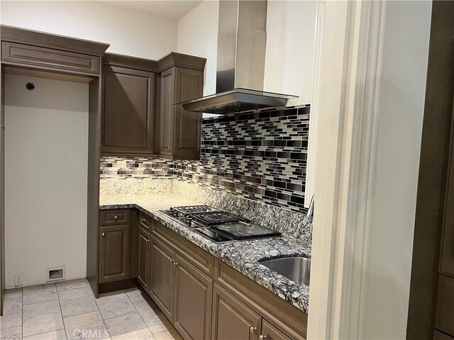 kitchen featuring tasteful backsplash, light stone counters, extractor fan, and gas cooktop