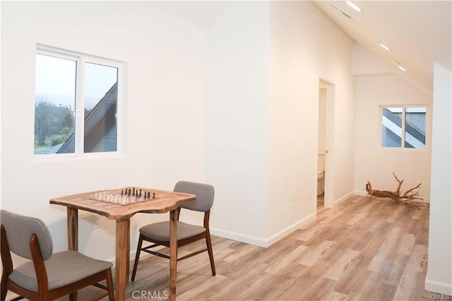 dining space featuring high vaulted ceiling and light hardwood / wood-style flooring