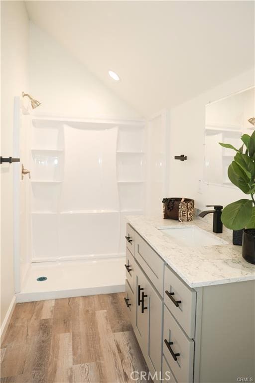 bathroom featuring hardwood / wood-style floors, vanity, vaulted ceiling, and walk in shower