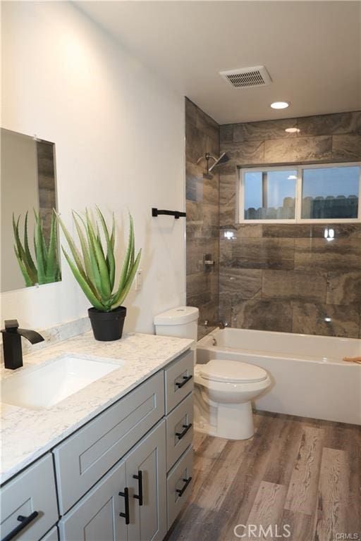 full bathroom featuring vanity, toilet, tiled shower / bath, and hardwood / wood-style flooring