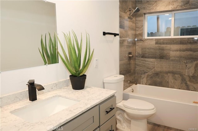 full bathroom featuring vanity, tiled shower / bath combo, and toilet