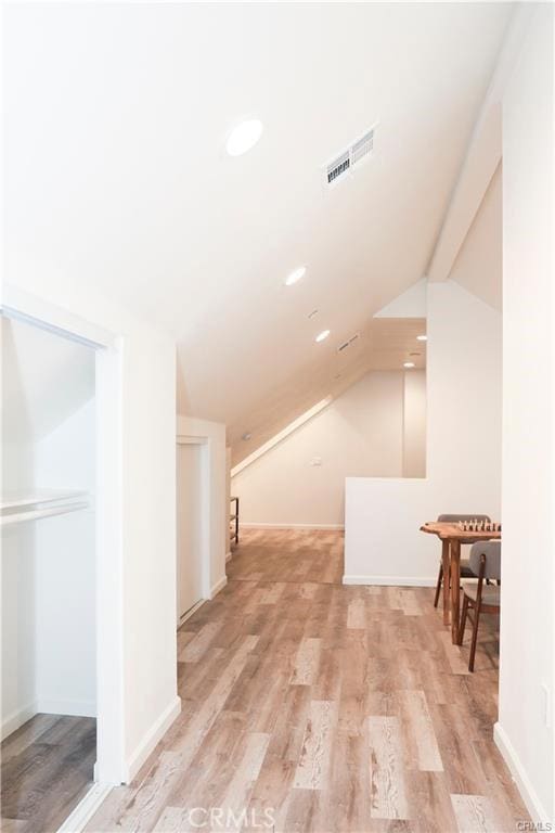 additional living space featuring light wood-type flooring and vaulted ceiling