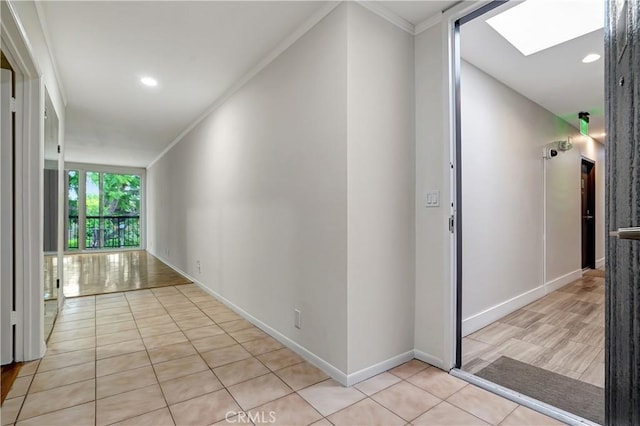 corridor featuring floor to ceiling windows, light tile patterned flooring, crown molding, and a skylight