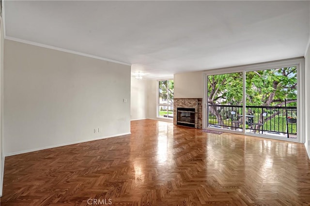 unfurnished living room featuring a stone fireplace, ornamental molding, and parquet flooring