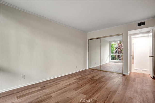 unfurnished bedroom featuring a closet, light hardwood / wood-style flooring, and ornamental molding