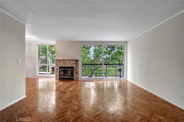 unfurnished living room featuring a healthy amount of sunlight, crown molding, parquet flooring, and a fireplace