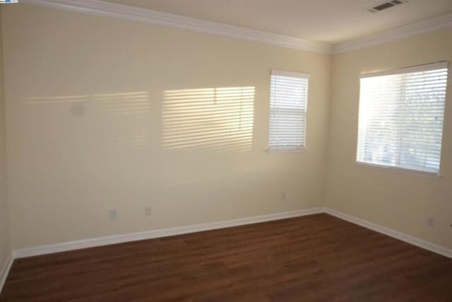 spare room featuring plenty of natural light, dark hardwood / wood-style floors, and ornamental molding