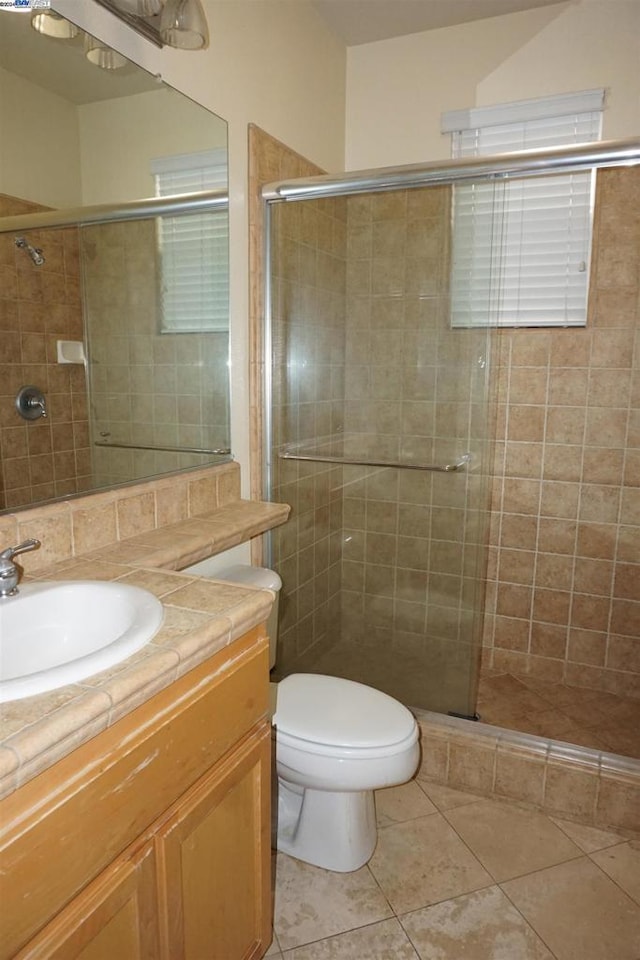 bathroom featuring tile patterned floors, vanity, toilet, and walk in shower