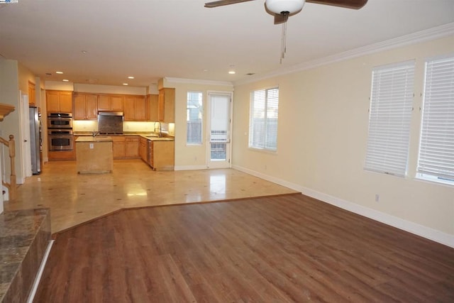 kitchen featuring a center island, crown molding, ceiling fan, light wood-type flooring, and appliances with stainless steel finishes