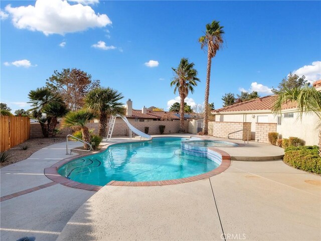 view of swimming pool featuring an in ground hot tub, a patio area, and a water slide