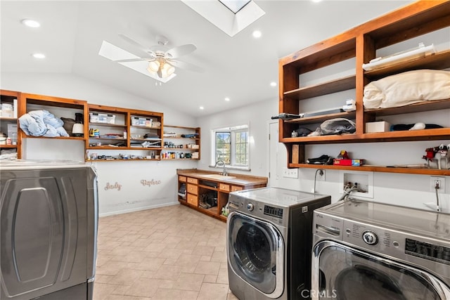 clothes washing area with washer and dryer, ceiling fan, sink, and a skylight