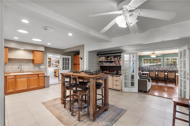 kitchen with beamed ceiling, a kitchen breakfast bar, sink, and french doors