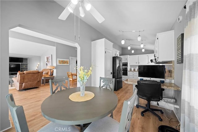 dining room featuring ceiling fan, light wood-type flooring, and vaulted ceiling