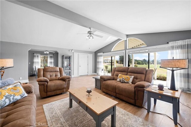 living room with a healthy amount of sunlight, lofted ceiling with beams, and light hardwood / wood-style flooring