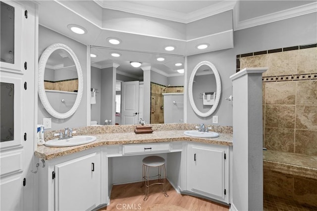 bathroom with vanity, wood-type flooring, tiled shower, and ornamental molding