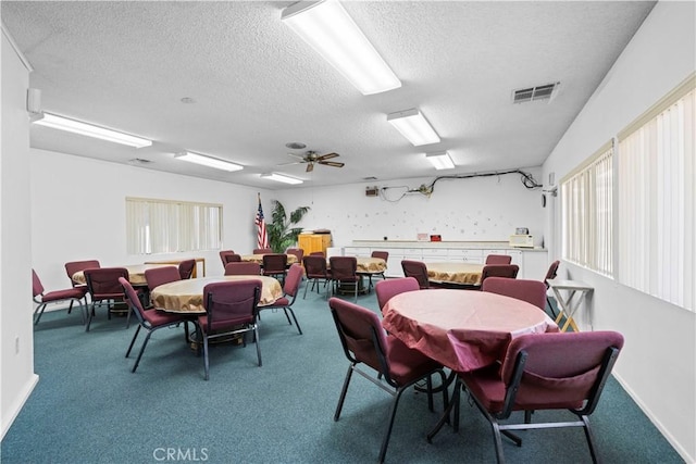 carpeted dining room featuring ceiling fan and a textured ceiling