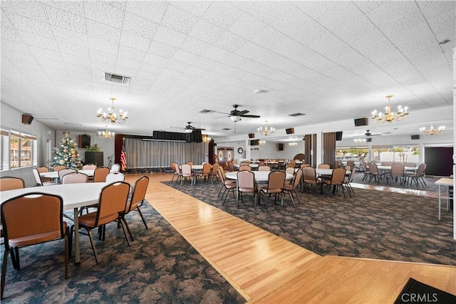 dining area featuring wood-type flooring and ceiling fan with notable chandelier