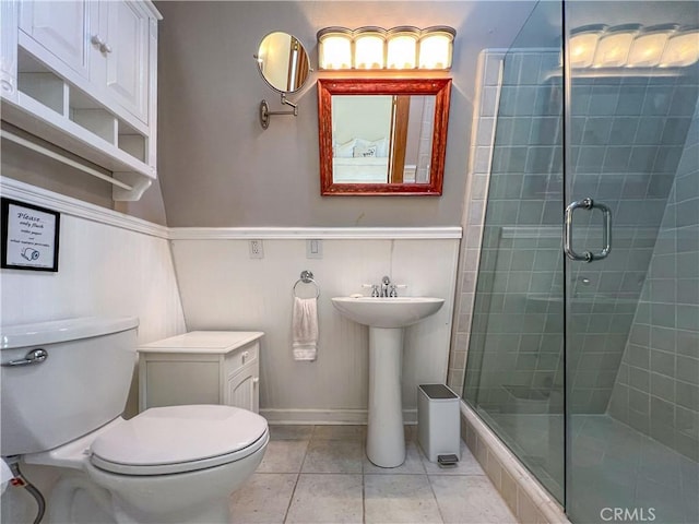 bathroom with tile patterned floors, toilet, a shower with shower door, and sink