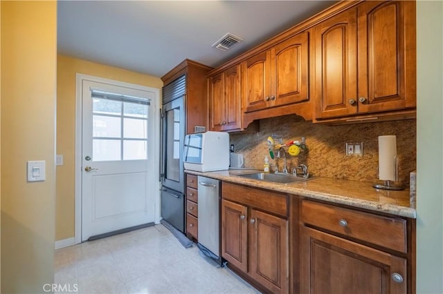 kitchen featuring stainless steel dishwasher, light stone counters, sink, and tasteful backsplash