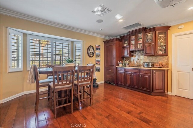 dining space with crown molding, dark hardwood / wood-style flooring, and indoor wet bar