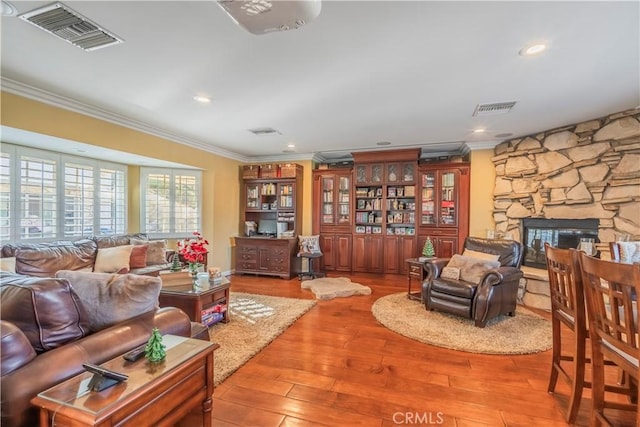 living room with a fireplace, light hardwood / wood-style floors, and crown molding