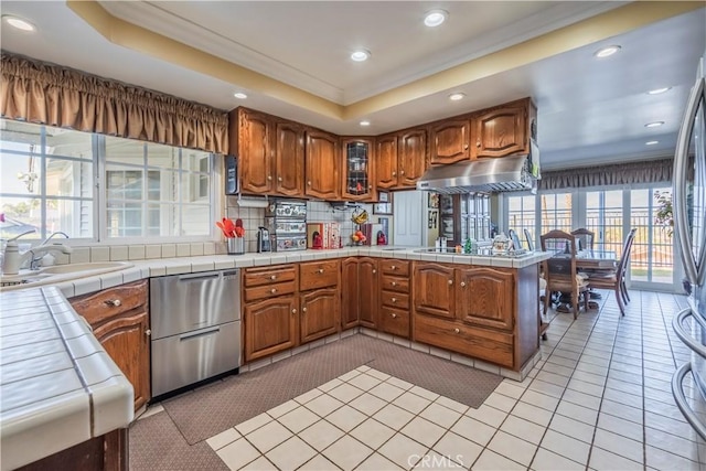 kitchen with dishwasher, sink, a raised ceiling, tile countertops, and kitchen peninsula