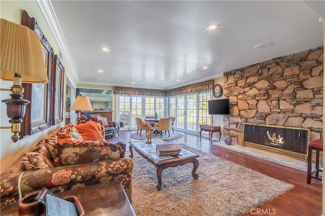 living room with hardwood / wood-style floors, a stone fireplace, and ornamental molding