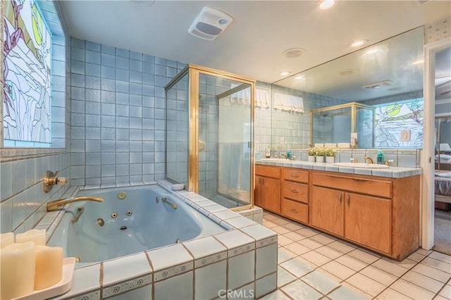 bathroom featuring shower with separate bathtub, vanity, tile patterned floors, and tile walls