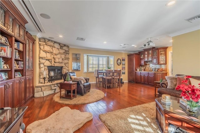 living room featuring dark hardwood / wood-style floors, crown molding, a fireplace, and bar area