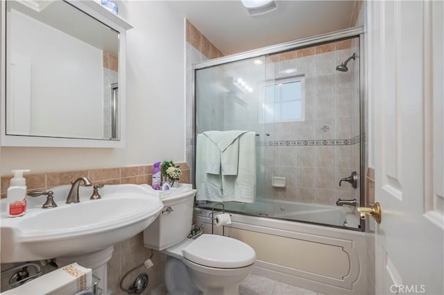 full bathroom with toilet, shower / bath combination with glass door, and sink