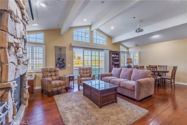 living room featuring vaulted ceiling with beams, a stone fireplace, and dark wood-type flooring