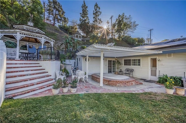 rear view of property featuring a pergola, a patio area, a yard, and a gazebo