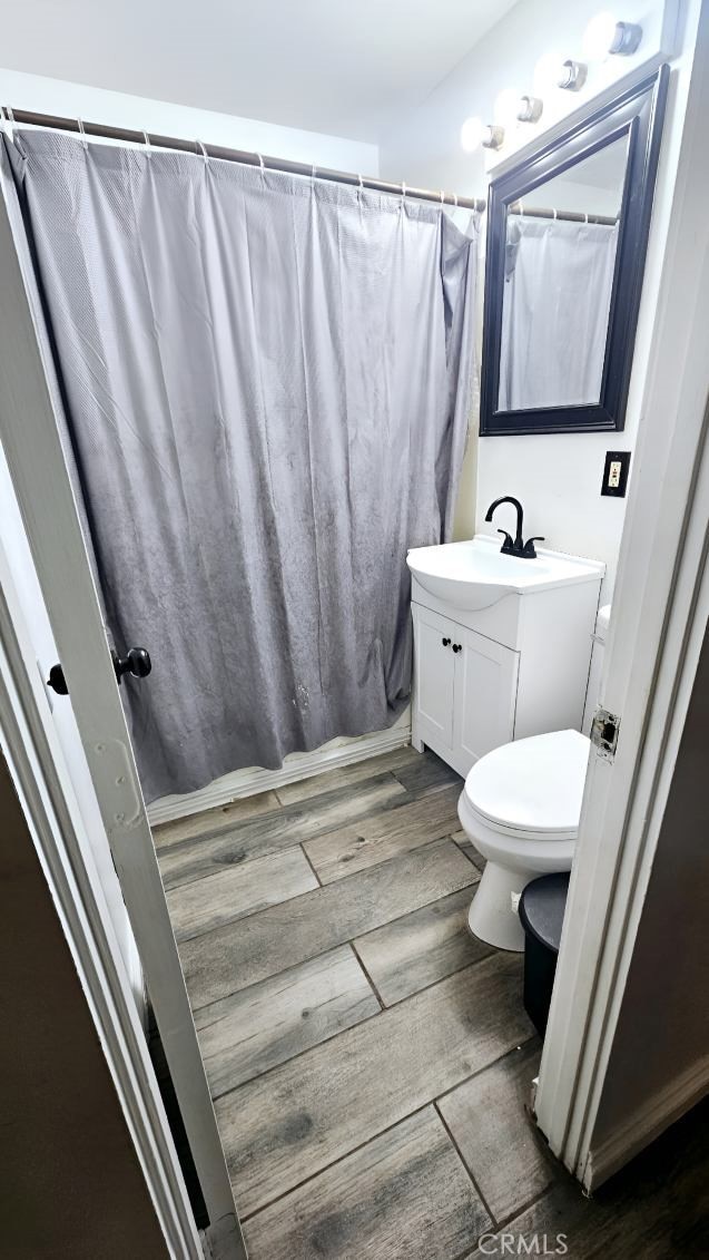 bathroom featuring hardwood / wood-style flooring, vanity, toilet, and walk in shower