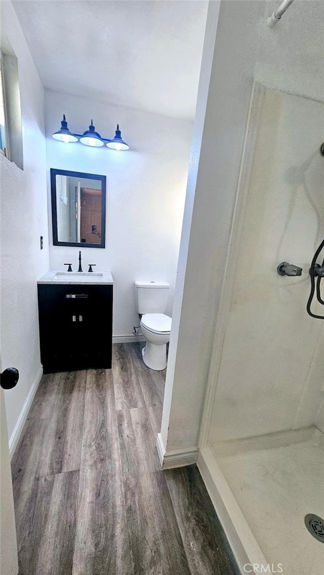 bathroom featuring vanity, a shower, hardwood / wood-style floors, and toilet