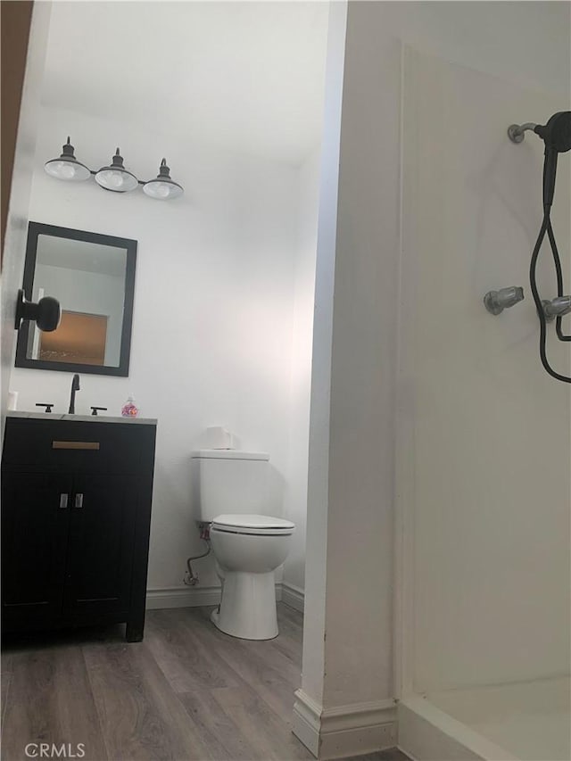 bathroom with vanity, hardwood / wood-style floors, toilet, and a shower