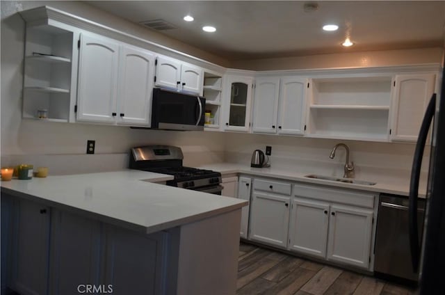 kitchen featuring sink, dark wood-type flooring, white cabinetry, stainless steel appliances, and kitchen peninsula