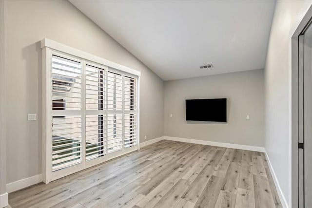 unfurnished living room with light hardwood / wood-style floors, plenty of natural light, and vaulted ceiling