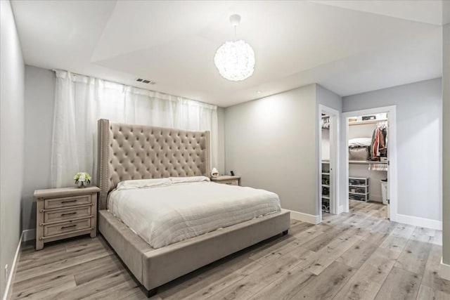 bedroom with a spacious closet, a closet, and light wood-type flooring