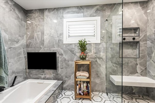 bathroom with tile walls and shower with separate bathtub